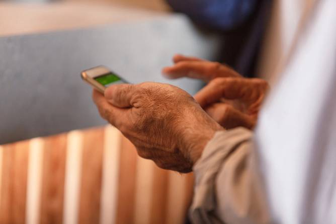 the hand of a senior citizen holding a cell phone