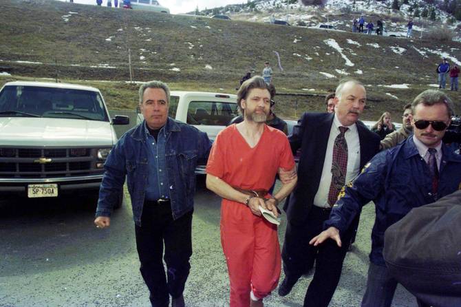 Theodore 'Ted' Kaczynski (in orange) is guided to his arraignment by federal marshals, Helena, Montana