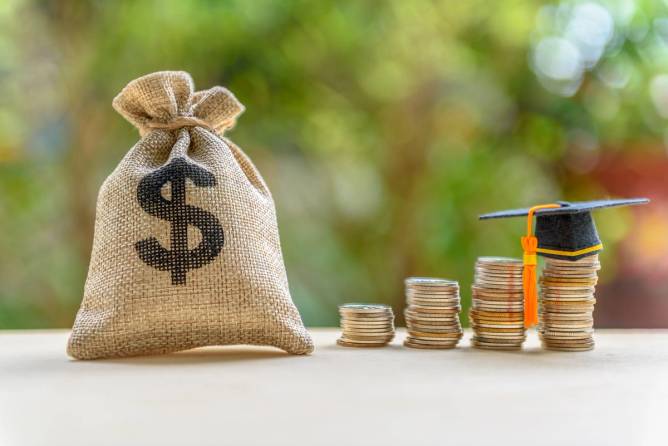 a burlap bag with a dollar sign, next to stacks of coins gradually getting taller; the final stack on the right has a little graduation cap on top