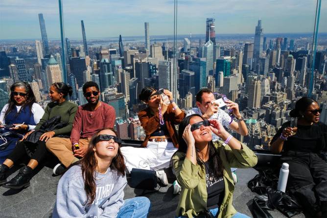 People look at the eclipse at the Edge at Hudson Yards