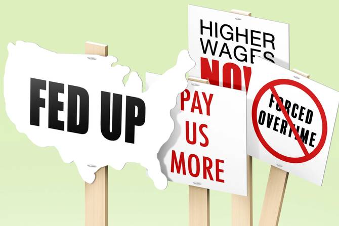Picket signs that read "Fed up" "Pay us more" "Higher wages now"  and crossed out "forced overtime"