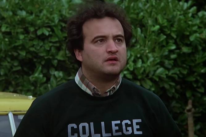 Jim Belushi wearing a sweatshirt that says "College" in Animal House