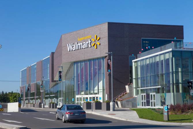 an outside image of a Walmart supercentre with a nearly empty parking lot in the foreground