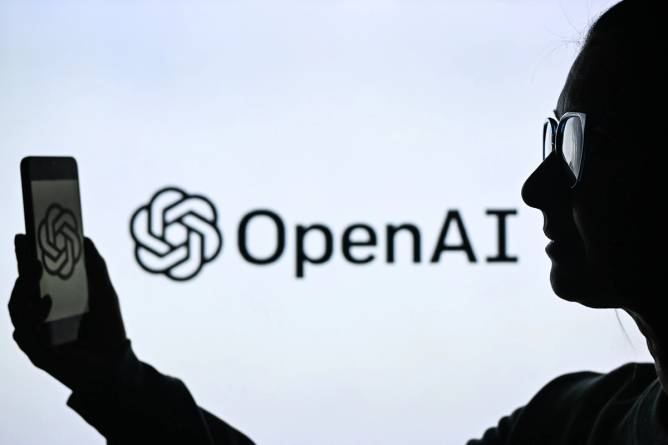 Person holding a phone in front of the OpenAI logo