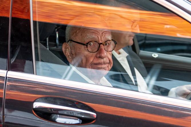 Rubert Murdoch looking out the window of a car