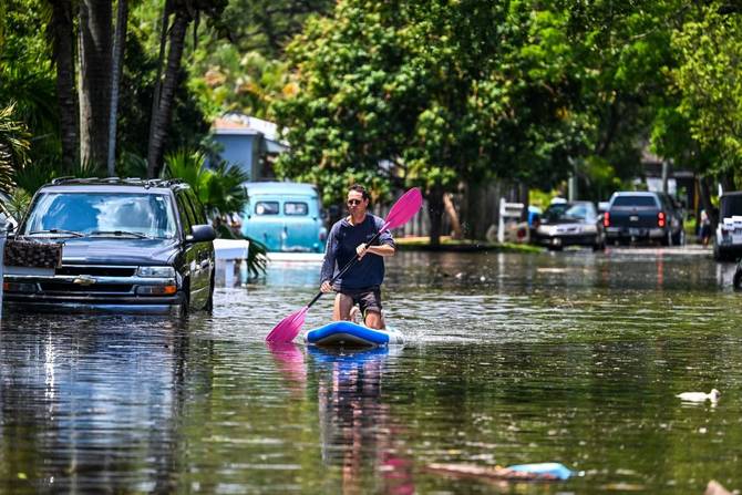 A man paddles on the flooded neighborhood after heavy rain in Fort Lauderdale, Florida