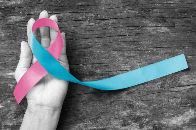 pink and blue ribbon in a black and white hand atop a black and white table 