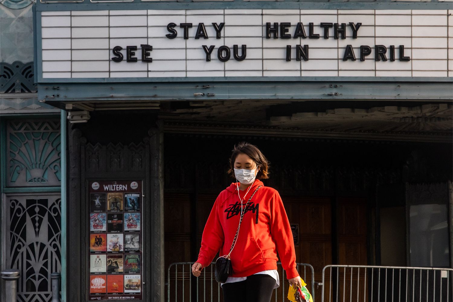 A woman walks wearing a mask to protect herself from the novel coronavirus (COVID-19) in front of a closed theater in Koreatown, Los Angeles.