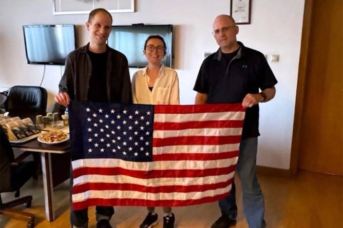 Wall Street Journal Reporter Evan Gershkovich, Radio Free Europe journalist Alsu Kurmasheva, and former U.S. Marine Paul Whelan pose with an American flag