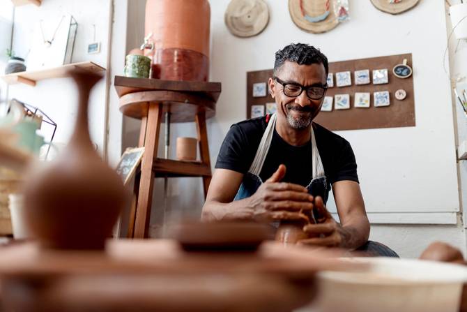 Smiling male artist making pottery in workshop
