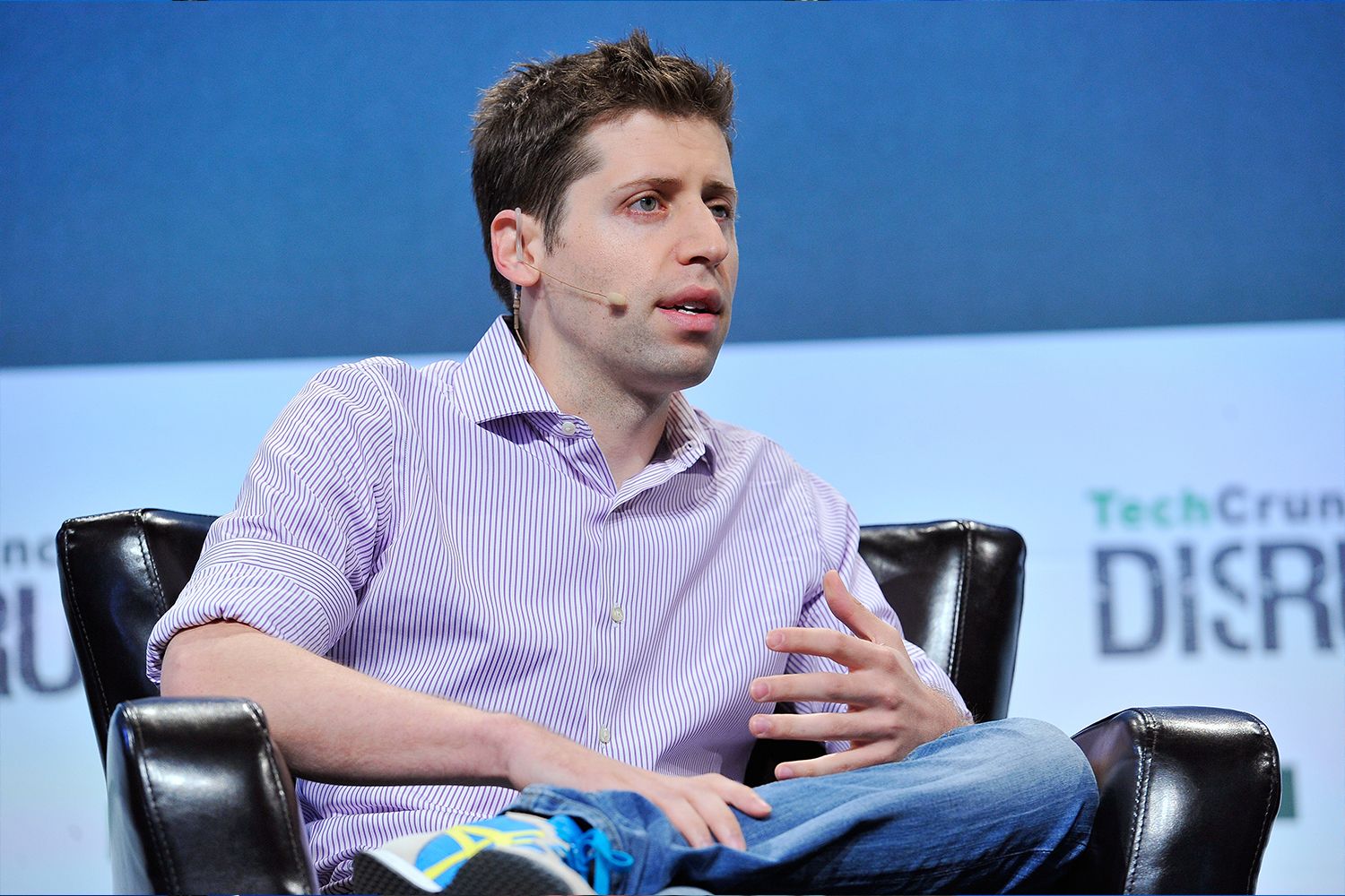 Sam Altman sits in a chair onstage at TechCrunch.