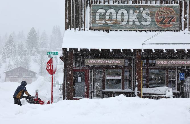 A worker uses a snowblower in front of a downtown business north of Lake Tahoe during a powerful multiple day winter storm in the Sierra Nevada mountains