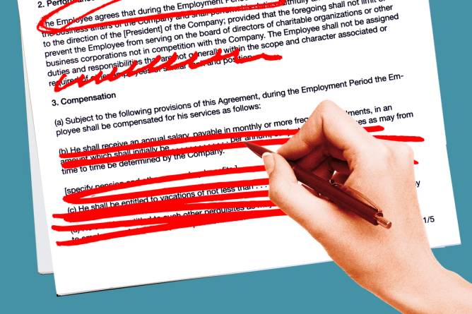 A hand holding a red pen crossing out words from a contract.