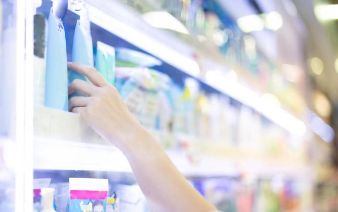 Hand reaching for skincare product on shelf