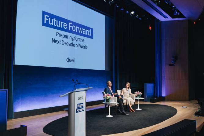 Two attendees at an event hosted by HR tech startup Deel are seated onstage, in front of a slide titled "Future Forward."
