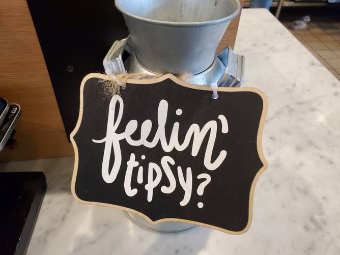 Close-up of comical tip jar with sign with pun reading Feelin Tipsy at Mendocino Farms restaurant in San Ramon, California