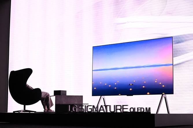 person in a chair watching a large television screen