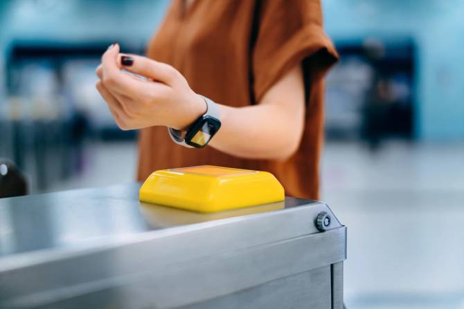 A woman swipes into a subway station using a smartwatch.