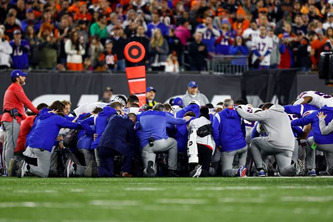 Buffalo Bills players and staff kneel together in solidarity after Damar Hamlin #3 sustained an injury during the first quarter of an NFL football game