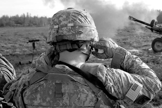 A member of the military covers their ears.