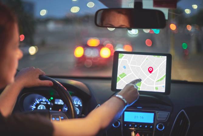 A woman sits in her car and uses a navigation system.