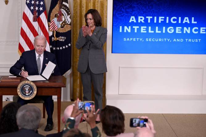 President Biden signing his executive order on AI with Vice President Kamala Harris standing next to him.