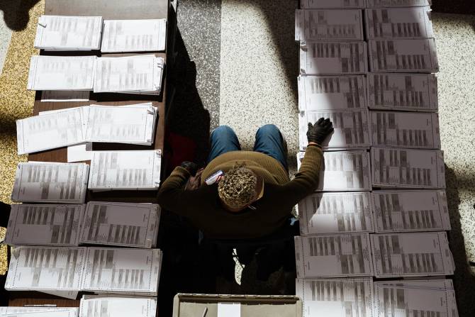 An election worker surrounded by blank ballots