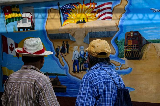 two people look at a mural of the north american continent