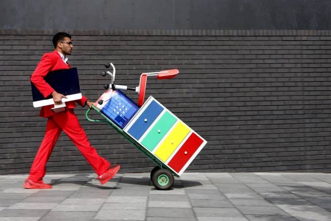 A person carries a computer and office supplies on a hand truck.