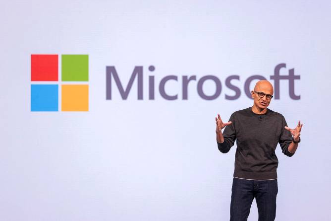 Microsoft CEO Satya Nadella in front of the company logo