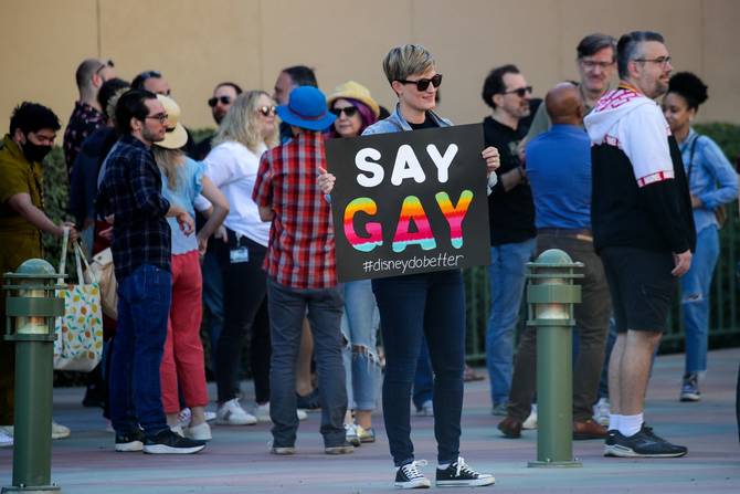 A Disney employee holds a sign that reads "say gay" outside of company offices. 