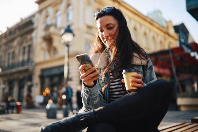 A woman holds a mobile phone.