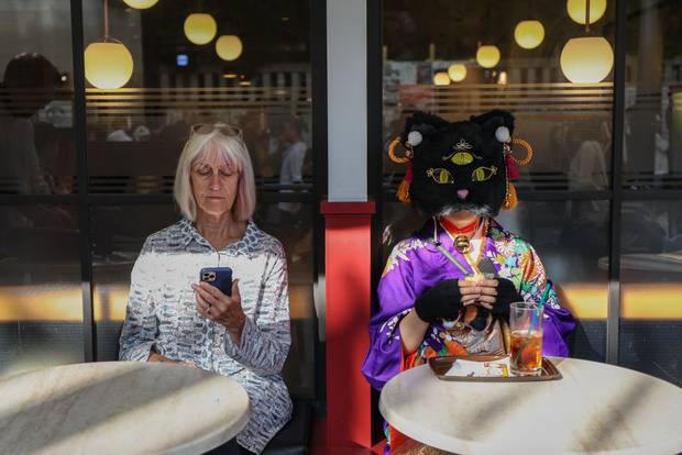 A participant sits at a cafe during Kagurazaka Bakeneko Festival on October 13, 2024 in Tokyo, Japan