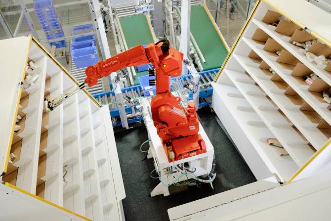 Two AI-powered robotic arms sort produce onto conveyer belts at a Covariant lab.