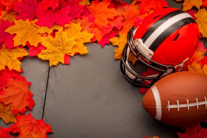 Football and helmet on leaf covered ground