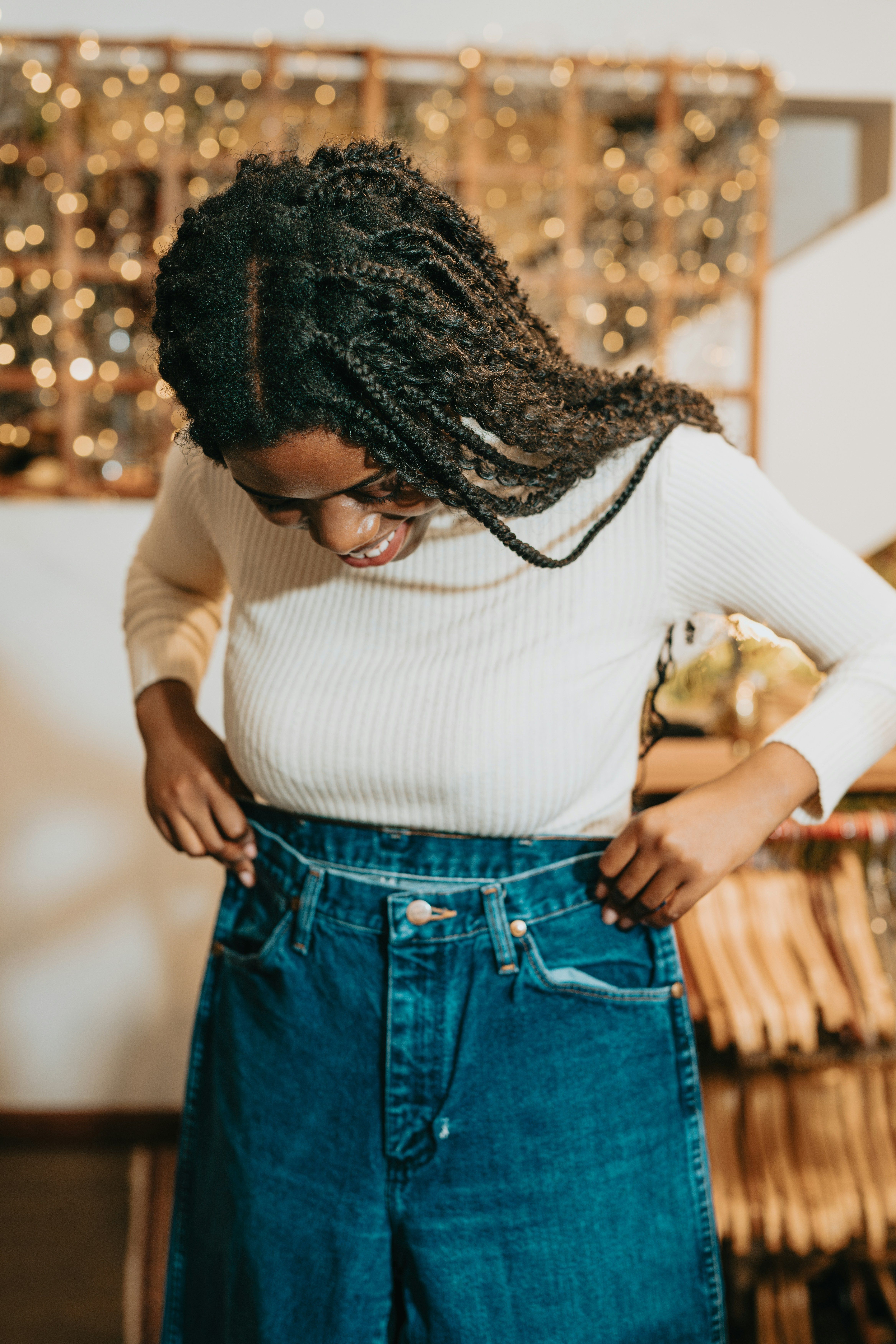 Woman holding up jeans to see if they fit.