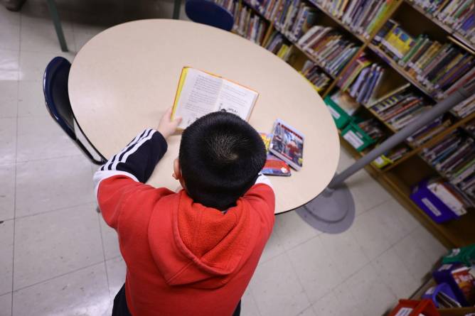 a child reading at a table in a library