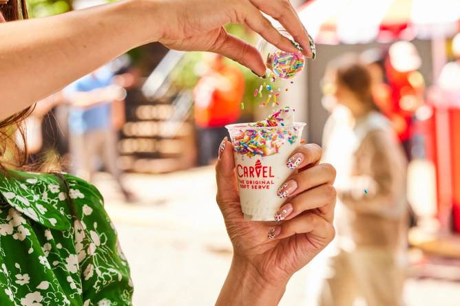Image of sprinkles being poured on a cup of soft serve ice cream.