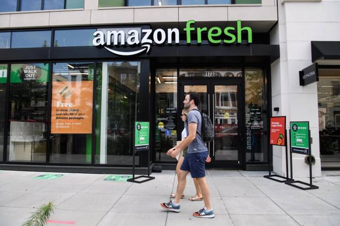 People walk in front of an Amazon Fresh store