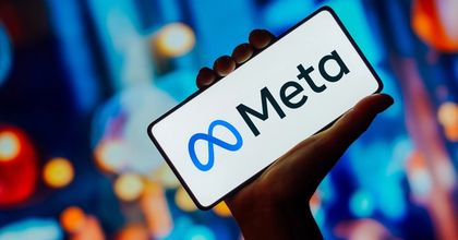 A person’s hand holding up a brightly-lit smartphone displaying the Meta logo