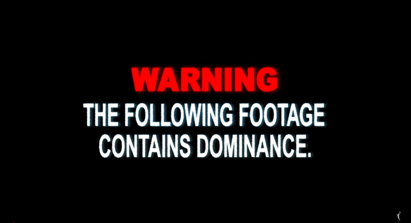 "WARNING: THE FOLLOWING FOOTAGE CONTAINS DOMINANCE." "Warning" is in red" and the remaining text is in white, over a black background 