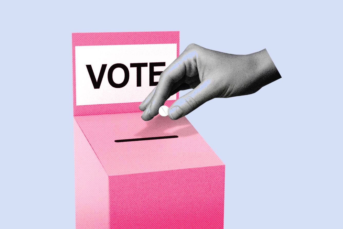Hand holding abortion pill over ballot box.