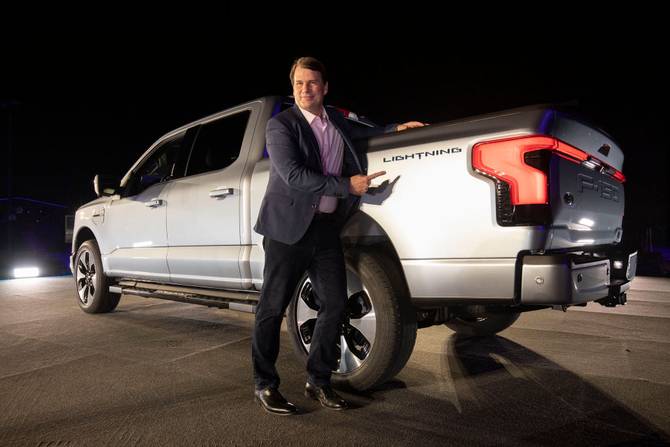 Ford CEO Jim Farley posing in front of an all-electric F-150 truck