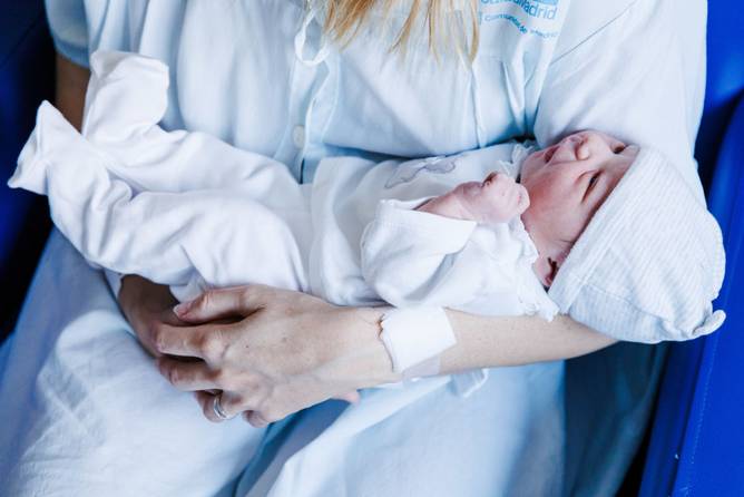 The first baby born in Spain of the New Year is held by her mother