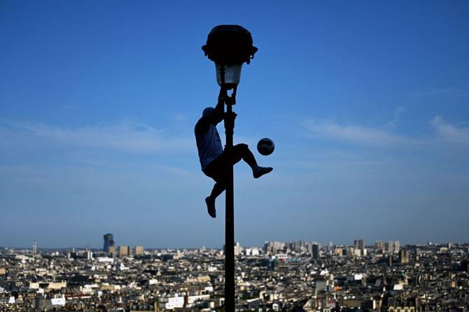 An artist holds on to a lamppost as he performs with a ball in the Montmatre district of Paris