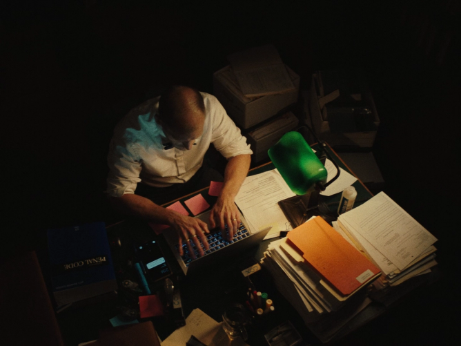 An attorney for the LA County Public Defender's Office sitting at a desk piled with paper.