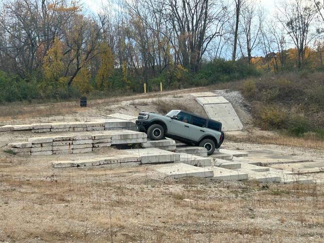 A Ford Bronco climbs up an off-road ledge at Ford's Michigan Proving Grounds.