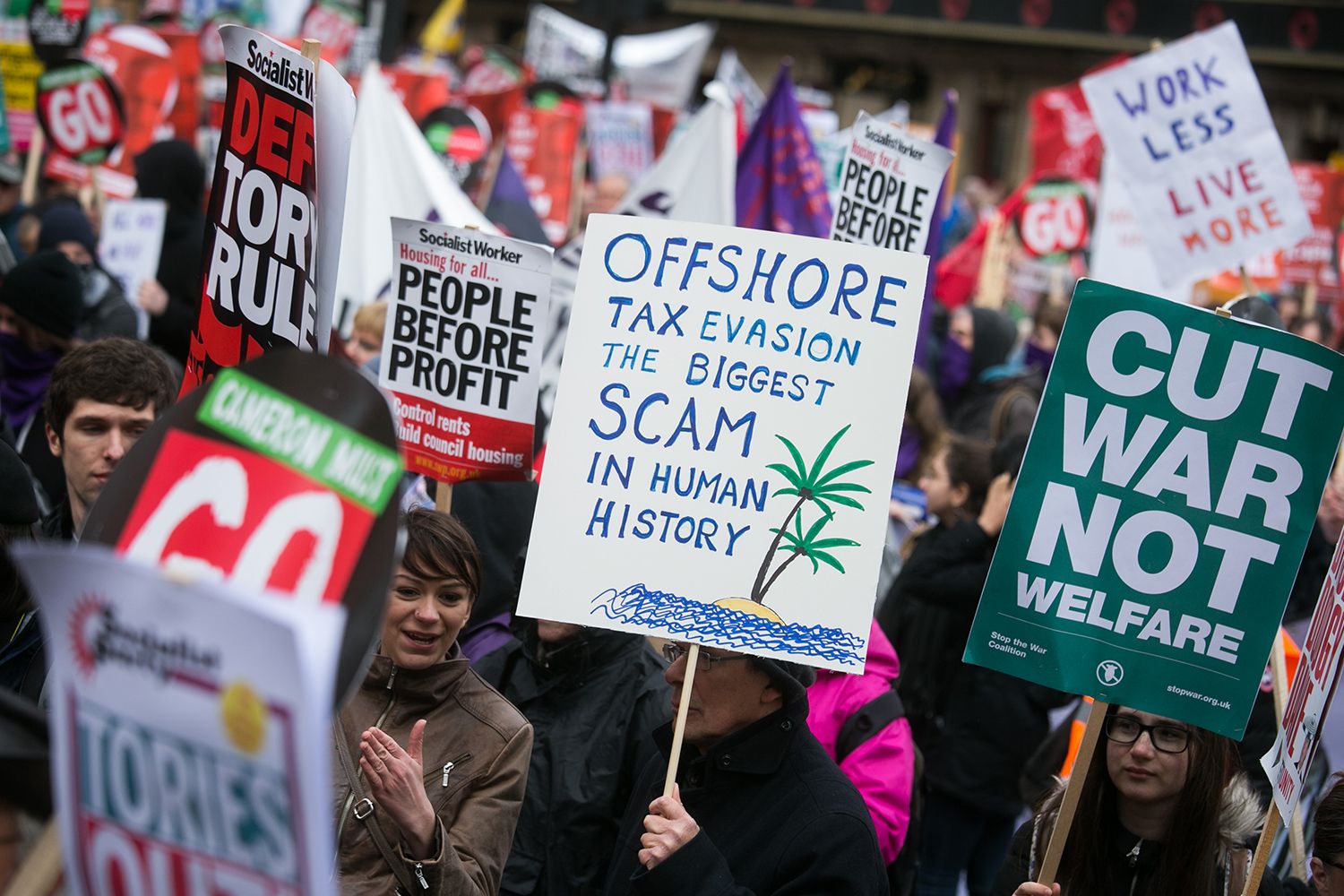 A person holds a placard that reads 'Off shore tax evasion the biggest scam in human history'.
