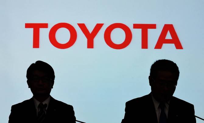 Silhouette of Toyota execs in front of the company's logo