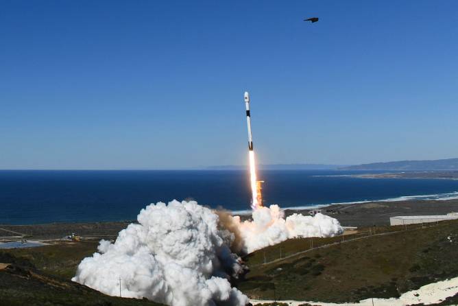 A SpaceX rocket launches next to the ocean 